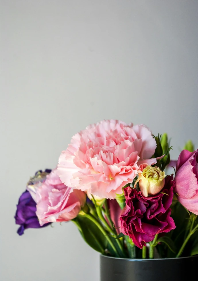 a black vase filled with pink and purple flowers